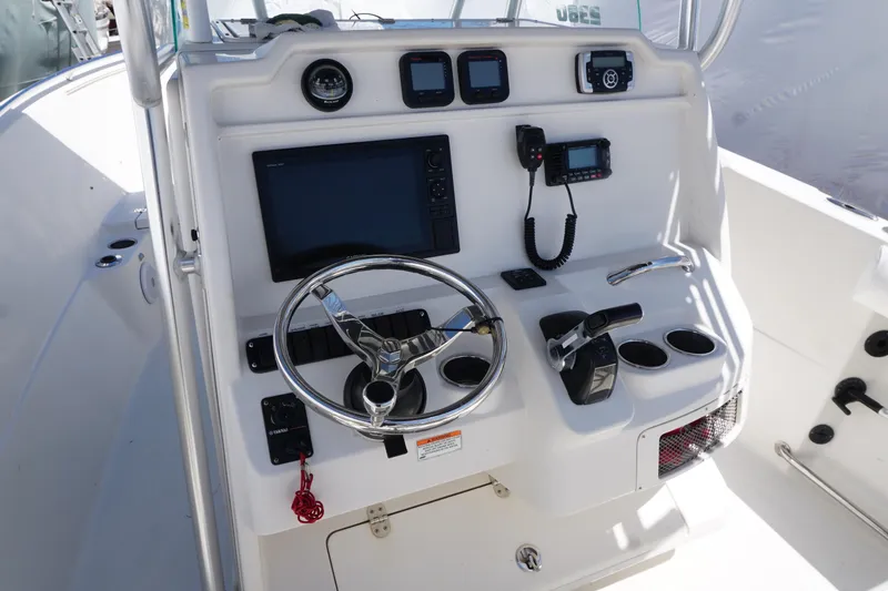 Slide: The Image of 2012 Sailfish 2380 CC boat console with steering wheel, navigation controls, and communication equipment. - 18