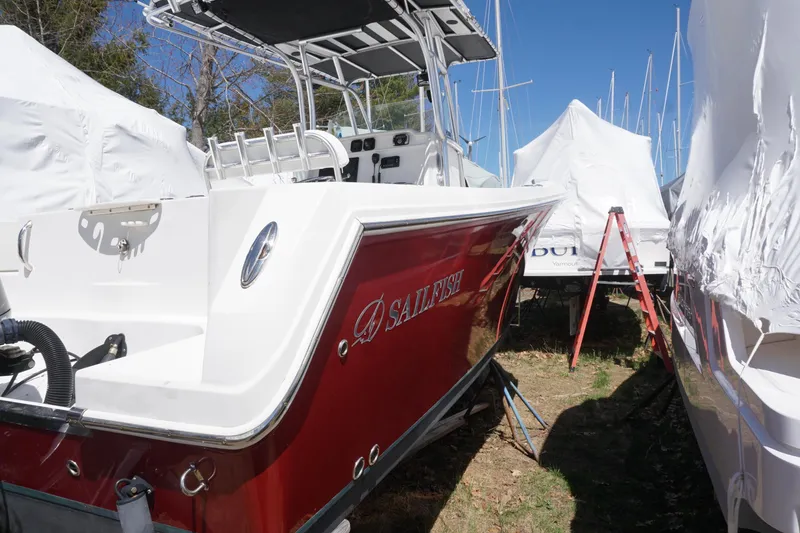 Slide: The Image of 2012 Sailfish 2380 CC boat in storage, red hull, outdoor setting. - 27