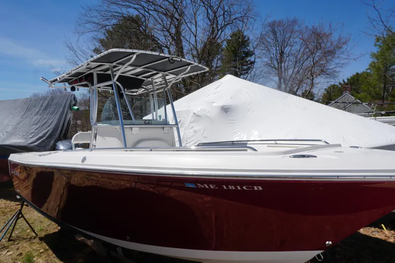 Slide: The Image of 2012 Sailfish 2380 CC boat with maroon hull, parked outdoors under clear sky. - 3