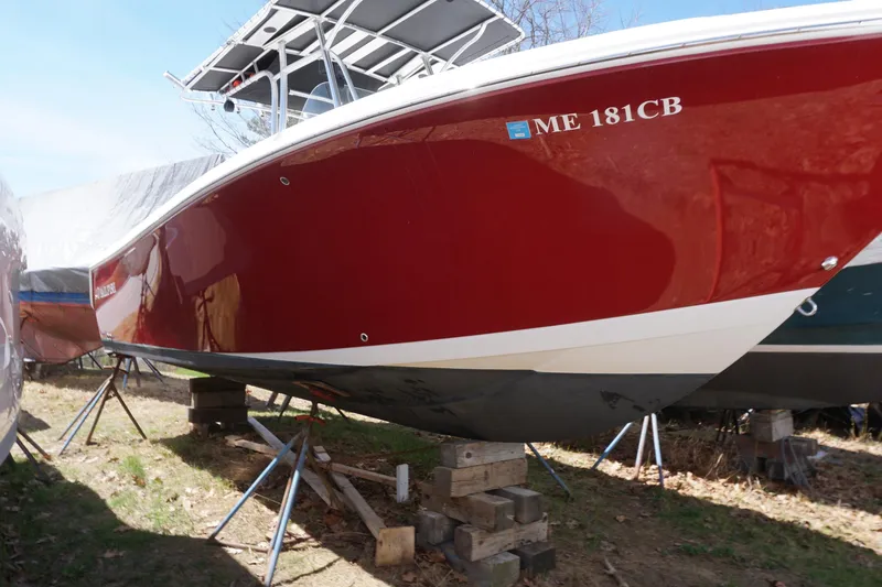 Slide: The Image of 2012 Sailfish 2380 CC boat with red hull on stands, outdoors. - 4