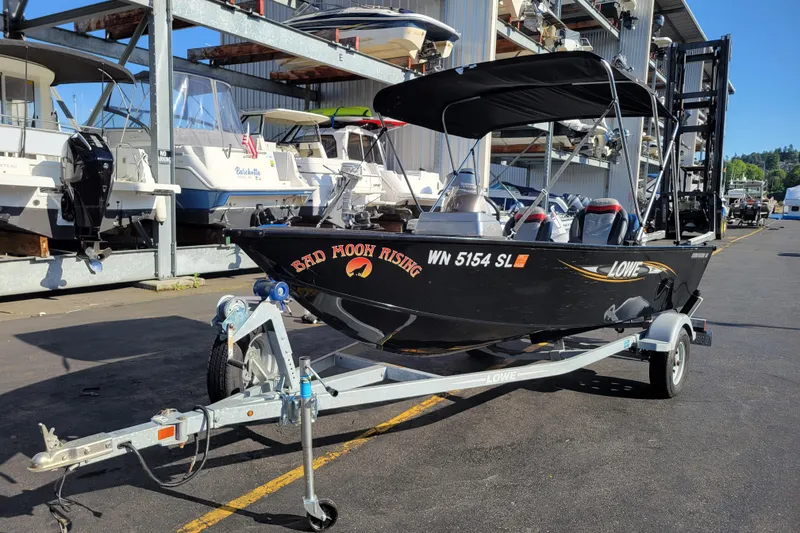 The Image of 2017 Lowe Fishing Machine 160S boat on trailer, parked at marina with other boats. - 0