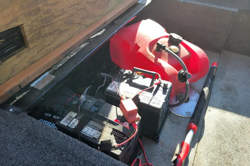 Slide: The Image of 2017 Lowe Fishing Machine 160S boat compartment with battery and red fuel tank. - 13