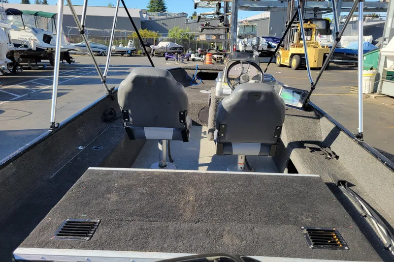 Slide: The Image of 2017 Lowe Fishing Machine 160S interior with dual seats and steering console in a marina setting. - 7