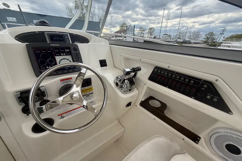 Slide: The Image of 2012 Boston Whaler 255 Conquest helm with steering wheel, controls, and navigation display. - 18