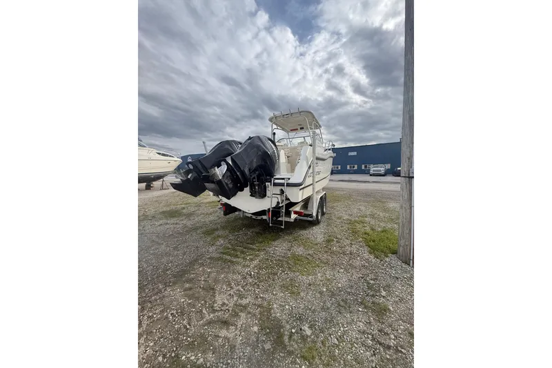 Slide: The Image of 2012 Boston Whaler 255 Conquest boat with dual engines on a trailer, under cloudy skies. - 35