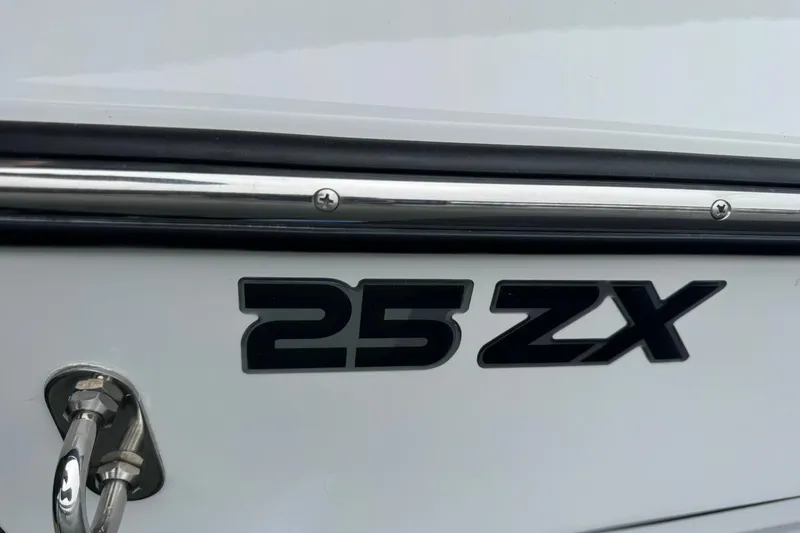 Slide: The Image of 2023 Tigé 25ZX boat emblem on white hull with chrome detailing. - 10