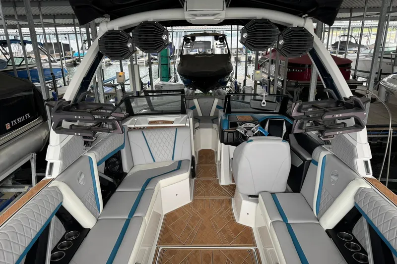 Slide: The Image of 2023 Tigé 25ZX boat interior with modern seating and audio system in a marina. - 15