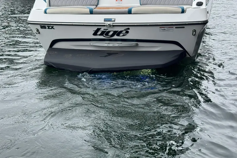 Slide: The Image of 2023 Tigé 25ZX boat rear view on water, showcasing sleek design and branding. - 2