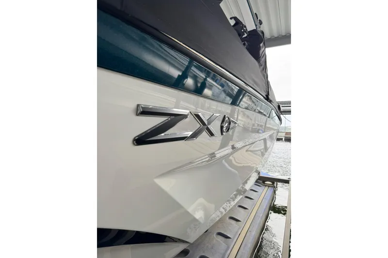 Slide: The Image of 2023 Tigé 25ZX boat side view with logo, docked by the water. - 3