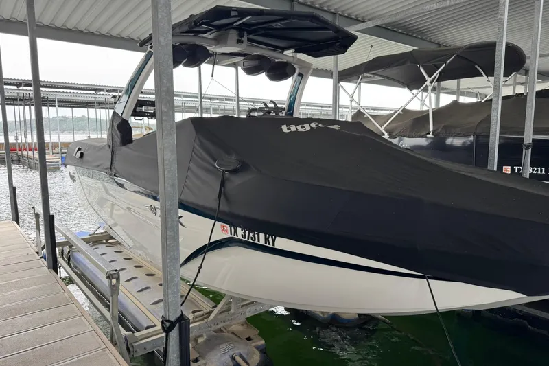 Slide: The Image of 2023 Tigé 25ZX boat covered and docked in a marina. - 9