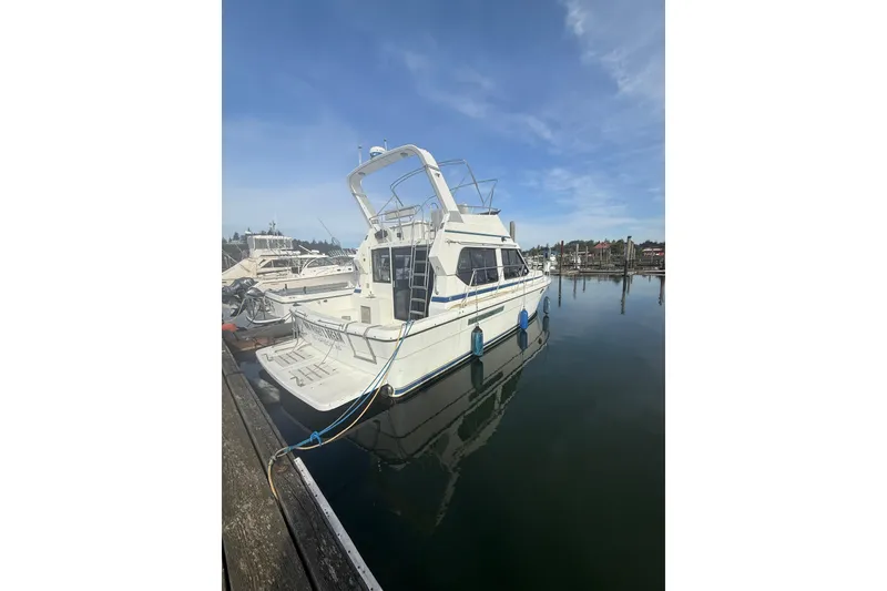 Slide: The Image of White 1990 Cooper Prowler boat docked in a marina under a clear blue sky. - 4
