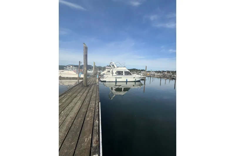 Slide: The Image of 1990 Cooper Prowler boat docked at a serene marina under a clear blue sky. - 5