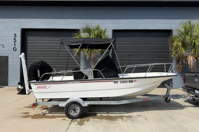 The Image of 2015 Boston Whaler 170 Montauk boat on trailer, parked outside a garage. - 1