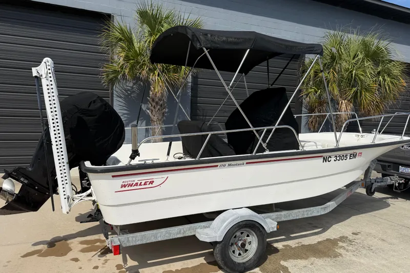 Slide: The Image of 2015 Boston Whaler 170 Montauk boat on trailer, parked near palm trees. - 3
