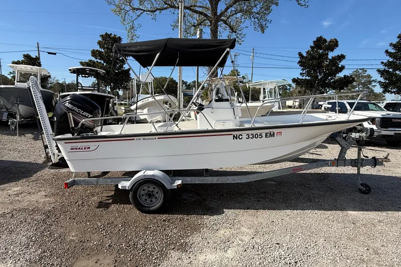Slide: The Image of 2015 Boston Whaler 170 Montauk boat on trailer, parked outdoors under clear sky. - 4