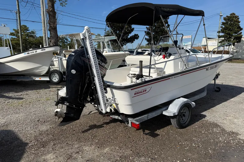 Slide: The Image of 2015 Boston Whaler 170 Montauk boat on trailer, parked outdoors, with outboard motor. - 7