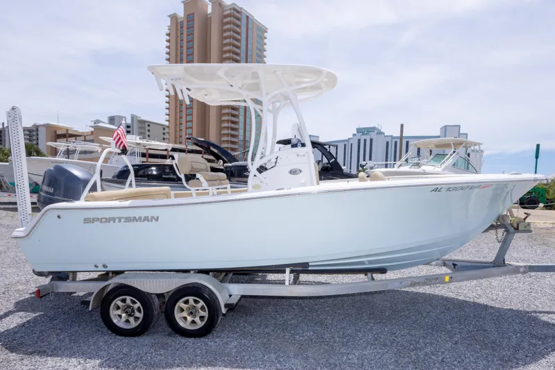 The Image of 2015 Sportsman Heritage 211 Center Console boat on trailer, urban backdrop. - 0