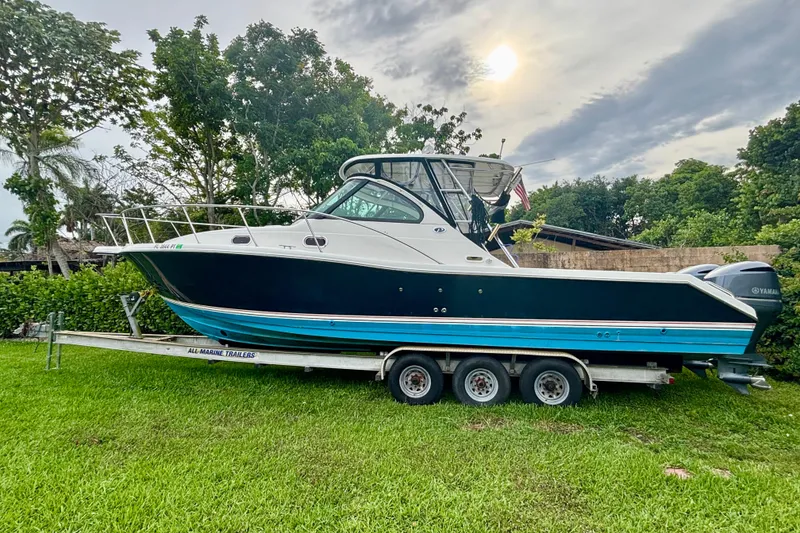 The Image of 2007 Pursuit 3370 Offshore boat on trailer, parked on grass with trees in background. - 0