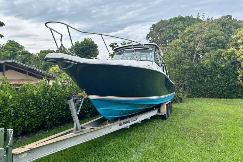 Slide: The Image of 2007 Pursuit 3370 Offshore boat on trailer, surrounded by lush greenery. - 18