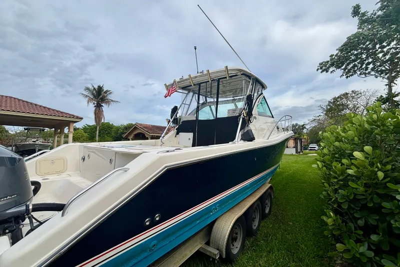 Slide: The Image of 2007 Pursuit 3370 Offshore boat on trailer, parked in a lush garden setting. - 19