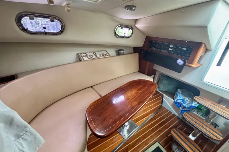 Slide: The Image of 2007 Pursuit 3370 Offshore cabin interior with beige seating and wooden table. - 2