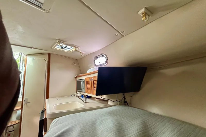 Slide: The Image of 2007 Pursuit 3370 Offshore cabin interior with kitchenette and TV. - 3