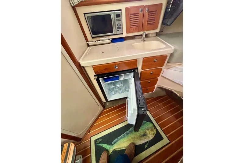 Slide: The Image of 2007 Pursuit 3370 Offshore boat kitchen with microwave, sink, and open fridge. - 6