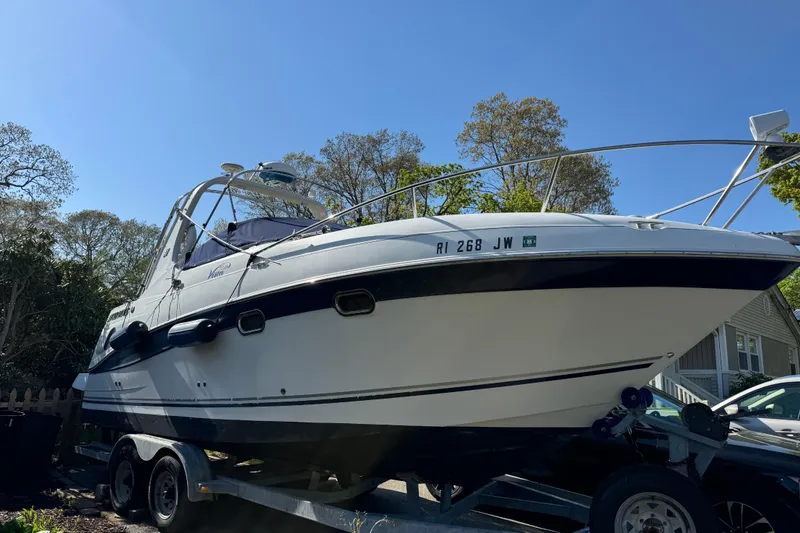 The Image of 2004 Four Winns 268 Vista boat on trailer, parked outdoors under clear blue sky. - 1