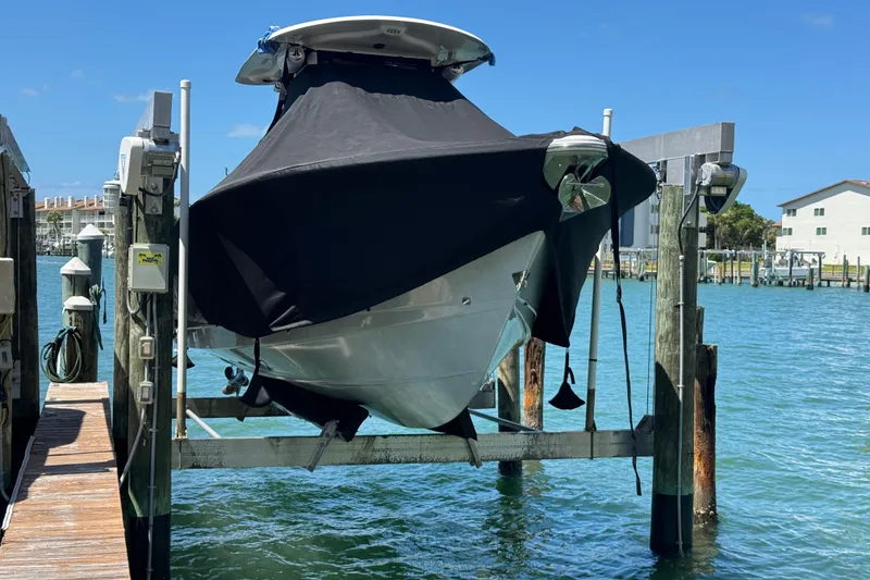 Slide: The Image of 2023 Sea Hunt Gamefish 27 boat covered and docked on a lift by the water. - 26