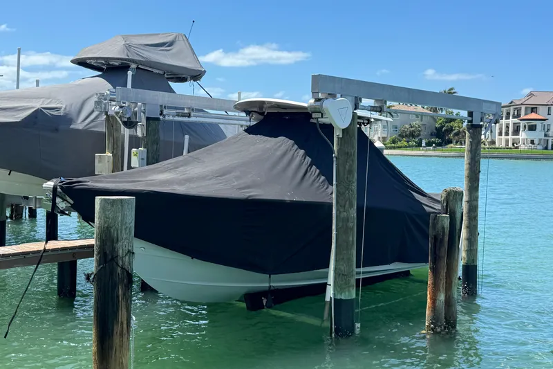 Slide: The Image of 2023 Sea Hunt Gamefish 27 boat covered and docked on a sunny day. - 27