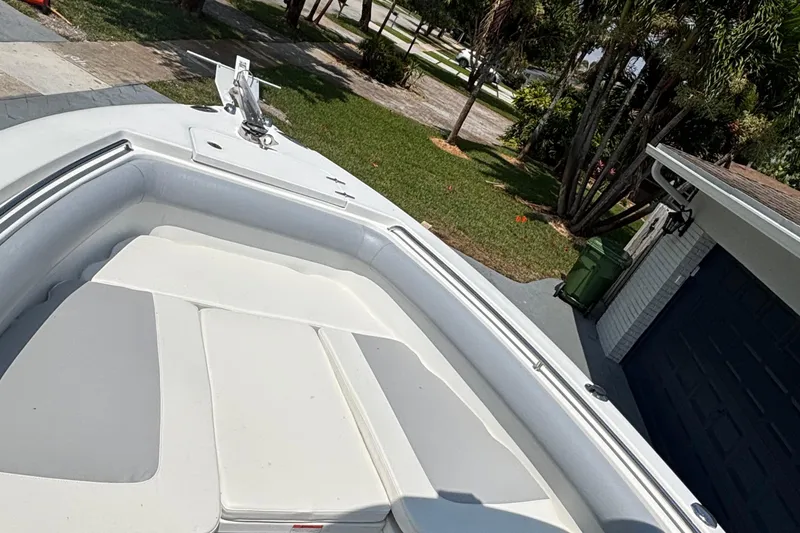Slide: The Image of 2011 Sea Hunt Gamefish 25 boat bow with cushioned seating, parked near a house. - 5