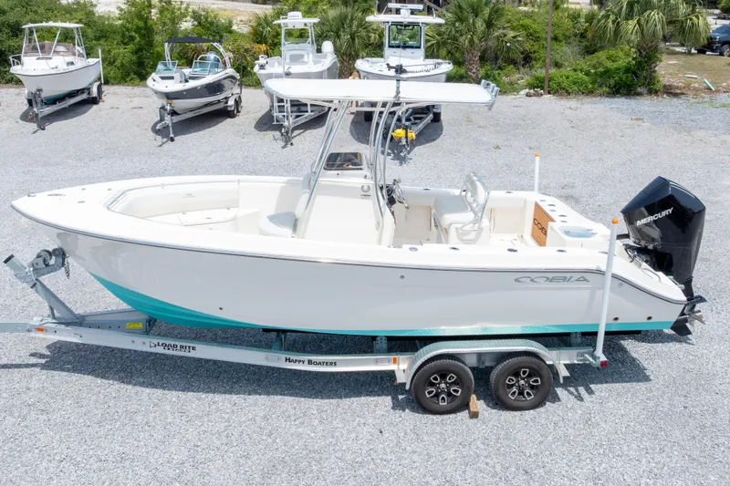 Slide: The Image of 2022 Cobia 237 Center Console boat on trailer, surrounded by other boats, in outdoor setting. - 10