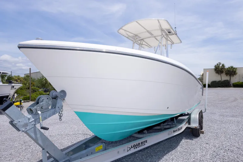 Slide: The Image of 2022 Cobia 237 Center Console boat on trailer, white and turquoise hull, sunny day. - 17