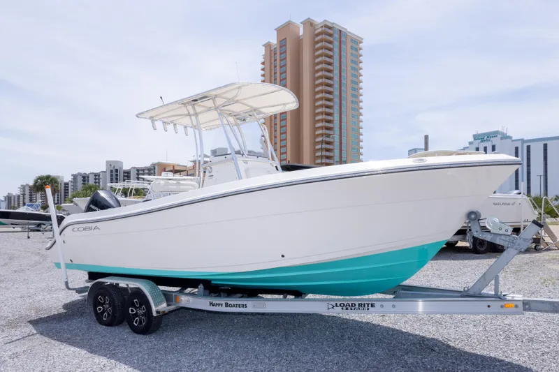 Slide: The Image of 2022 Cobia 237 Center Console boat on trailer, parked on gravel lot. - 2