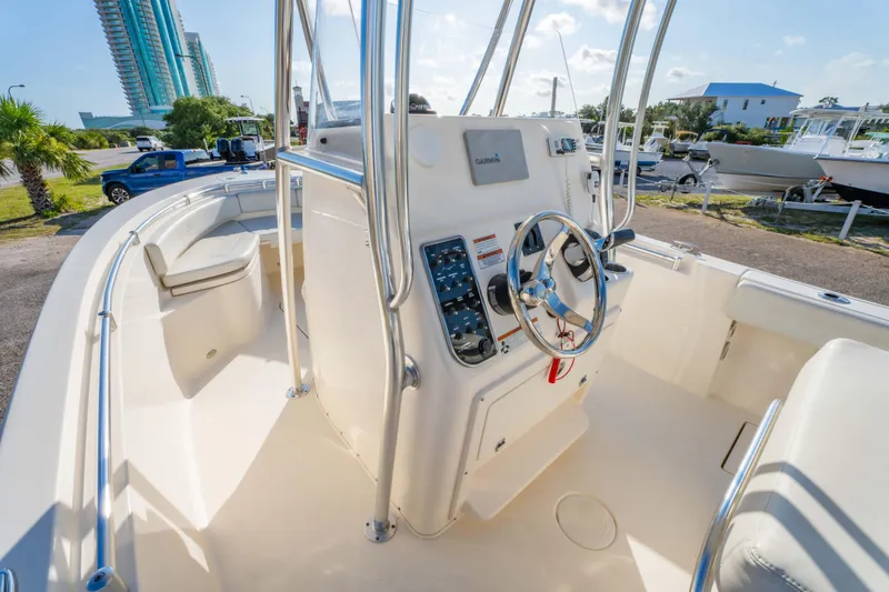 Slide: The Image of 2022 Cobia 237 Center Console boat interior with steering wheel and seating, docked outdoors. - 26