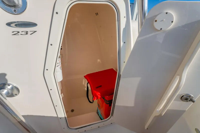 Slide: The Image of Open storage compartment on 2022 Cobia 237 Center Console boat with safety equipment. - 36
