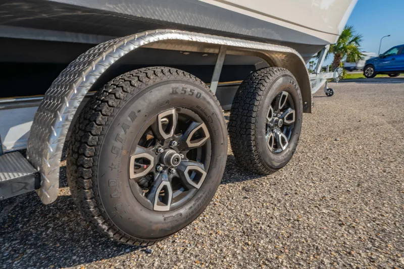 Slide: The Image of Trailer wheels of a 2022 Cobia 237 Center Console boat on gravel surface. - 37