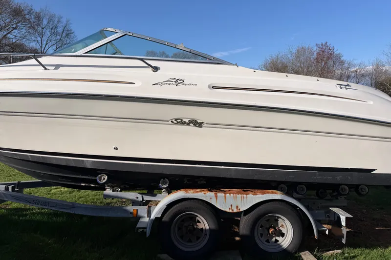 Slide: The Image of 2000 Sea Ray 215 Express Cruiser on trailer, side view, outdoors. - 10