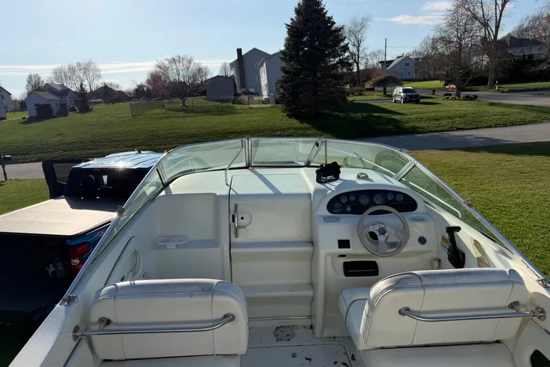 Slide: The Image of 2000 Sea Ray 215 Express Cruiser interior with steering wheel and dashboard, parked in a suburban area. - 4