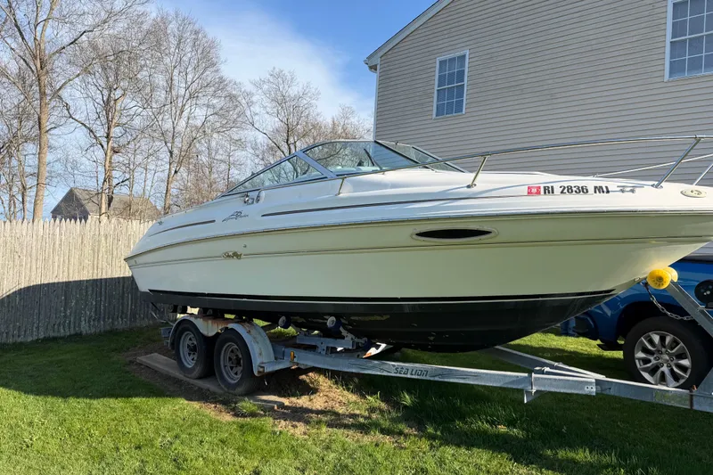 Slide: The Image of 2000 Sea Ray 215 Express Cruiser on trailer, parked in a residential yard. - 8