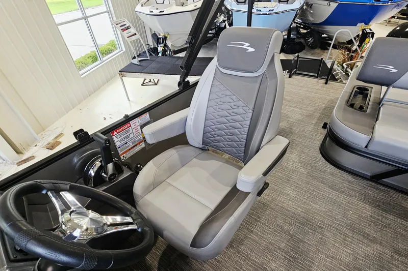 Slide: The Image of 2024 Bennington 22 S Swingback boat interior with gray captain's chair and steering wheel. - 10