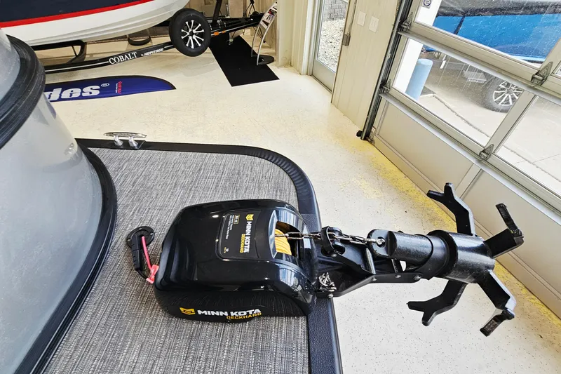 Slide: The Image of 2024 Bennington 22 S Swingback with Minn Kota Deckhand anchor system in a garage setting. - 15