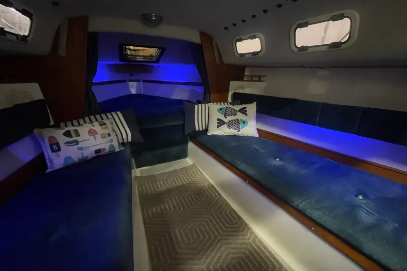 Slide: The Image of Interior of a 2001 Precision 23 sailboat with blue lighting and decorative pillows. - 10