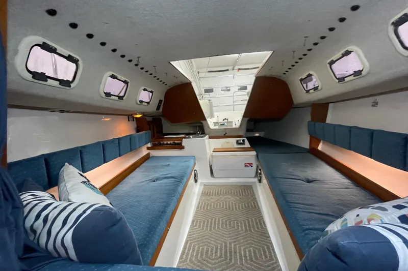 Slide: The Image of Interior of a 2001 Precision 23 sailboat with blue cushioned seating and multiple windows. - 13