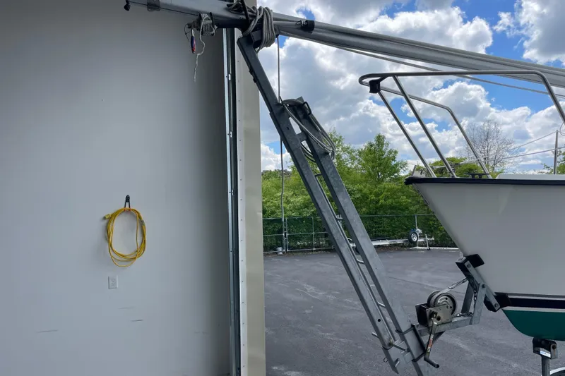 Slide: The Image of Boat trailer with Precision 23 sailboat, 2001 model, parked near a garage under a cloudy sky. - 31