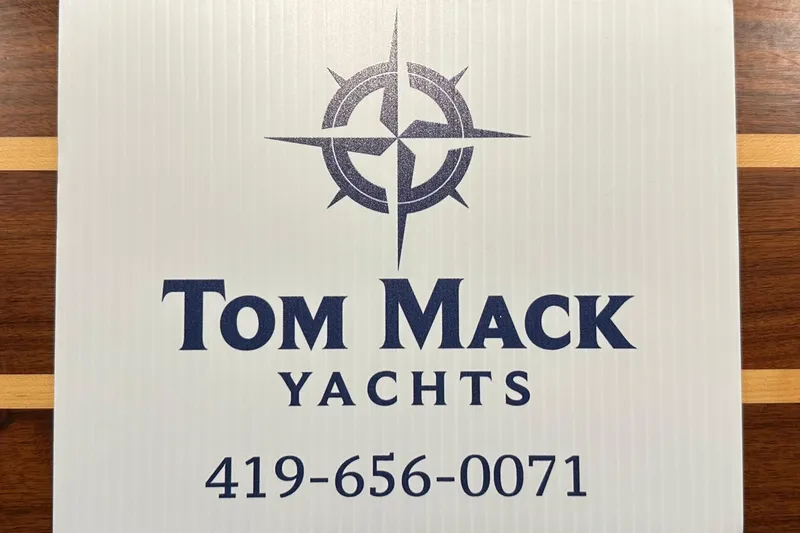 Slide: The Image of Tom Mack Yachts logo with contact number, featuring a nautical compass design. - 47