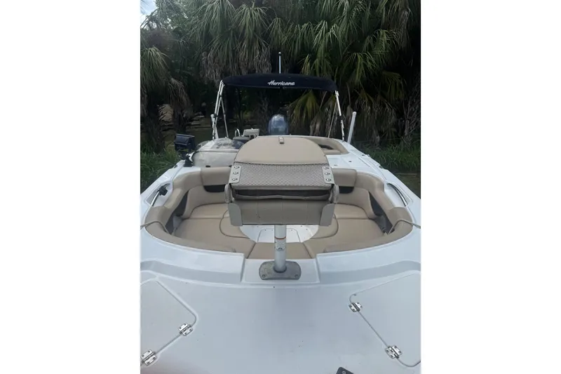 Slide: The Image of 2016 Hurricane SunDeck Sport 203 OB boat with seating, docked near palm trees. - 15