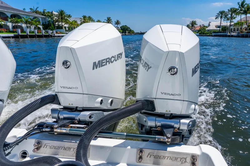 Slide: The Image of Twin Mercury Verado engines on a 2019 Freeman 42LR boat cruising in a scenic waterway. - 42