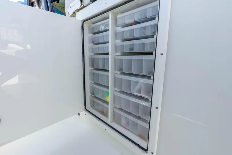 Slide: The Image of Open storage compartment with organized containers on a 2019 Freeman 42LR boat. - 51