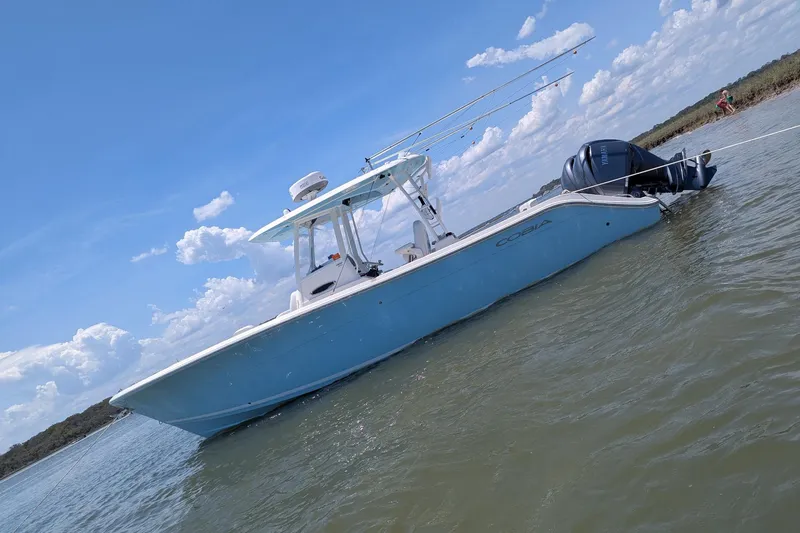 The Image of 2023 Cobia 301 Center Console boat anchored in calm waters under a clear blue sky. - 24